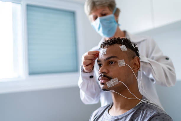 Doctor placing electrodes on patient's head for a polysomnography (sleep study)
